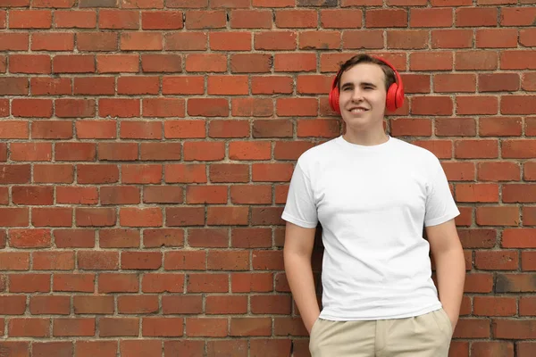 Przystojny Młodzieniec Słuchawkami Przy Ścianie Czerwonej Cegły Miejsce Tekst — Zdjęcie stockowe