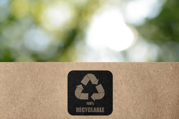 緑の背景がぼやけてリサイクルのシンボルを持つ紙袋 環境に優しいパッケージ — ストック写真