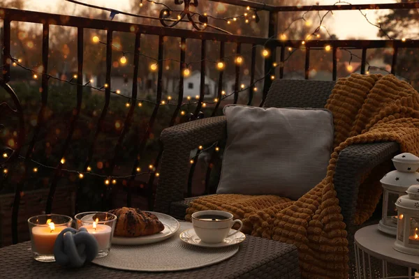 Beautiful view of garden furniture with pillow, soft blanket and burning candles at balcony