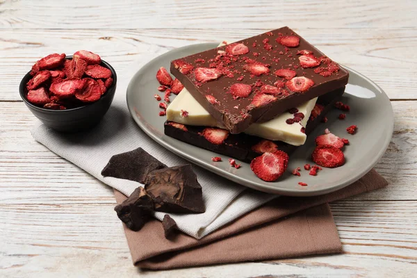 stock image Plate and different chocolate bars with freeze dried fruits on white wooden table