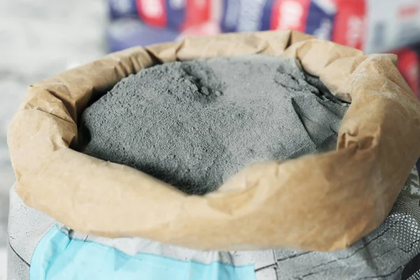 Cement powder in bag on blurred background, closeup view