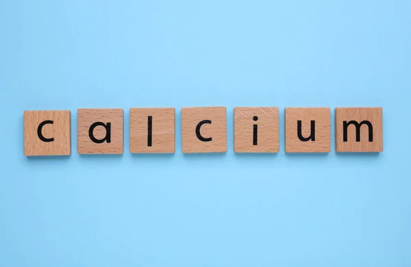 stock image Word Calcium made of wooden cubes with letters on turquoise background, top view