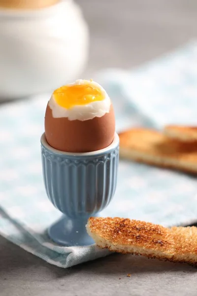 Tasty boiled chicken egg with toasted bread on grey table