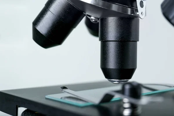 Modern medical microscope with glass slide on grey background, closeup