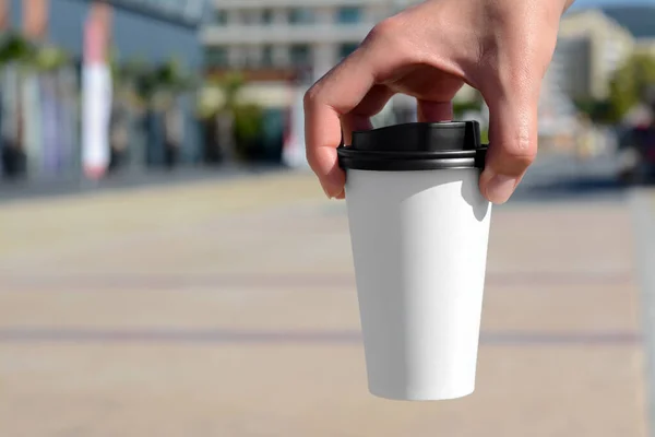 Woman holding takeaway coffee cup outdoors, closeup. Space for text