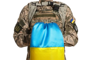 Beyaz arka planda Ukrayna bayrağı olan askeri üniformalı asker, yakın plan.
