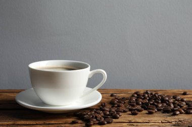 Ahşap masada bir fincan aromatik kahve ve fasulye. Metin için boşluk