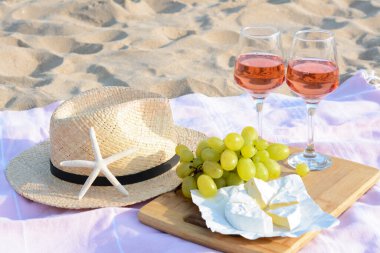 Kumsalda kumsalda piknik yapmak için gül şarabı ve atıştırmalık bardaklar