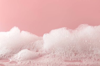 Pembe arka planda tüylü banyo köpüğü, yakın plan.