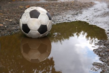 Çamurlu su birikintisinde kirli futbol topu, mesaj için yer