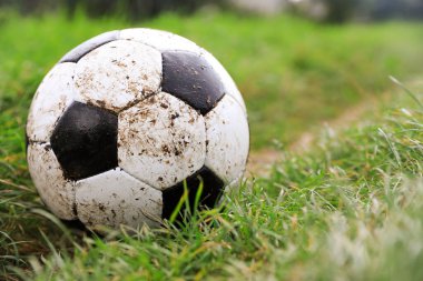 Yeşil çimlerin üzerinde kirli futbol topu, yakın plan. Metin için boşluk