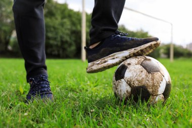 Yeşil çimlerin üzerinde kirli futbol topu olan adam, yakın plan.