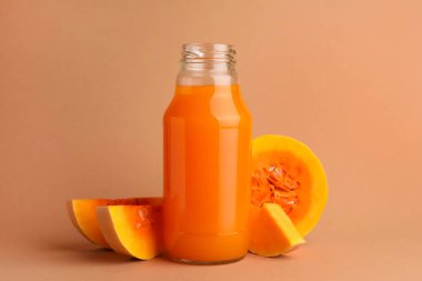 Cam şişede lezzetli balkabağı suyu ve soluk turuncu arka planda balkabağı.