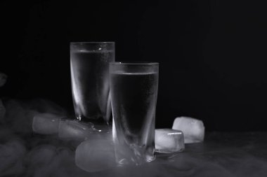 Siyah arka planda buzlu shot bardaklarında votka.