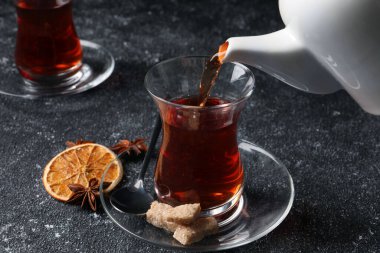 Geleneksel Türk çayını çaydanlıktan bardağa döküyor Gri dokulu masaya, yakın plan
