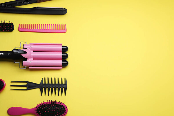 Flat lay composition of professional hairdresser tools on yellow background, space for text