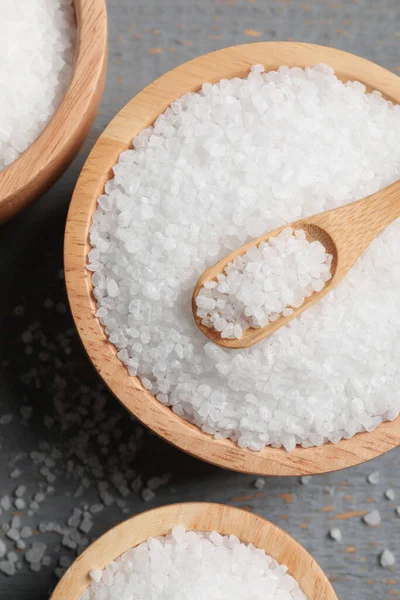 stock image Bowls of natural sea salt on grey wooden table, flat lay