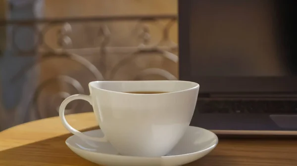 วยกาแฟหอมและแล อปบนโต ะไม างนอก ใกล — ภาพถ่ายสต็อก