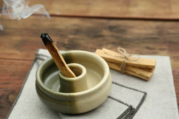 stock image Palo Santo stick smoldering in holder on wooden table