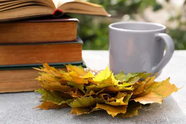 stock image Yellow maple leaves, books and cup of tea on light gray table, closeup. Autumn atmosphere