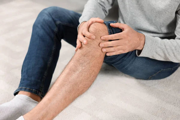 Man Met Pijn Zijn Been Wit Tapijt Close — Stockfoto