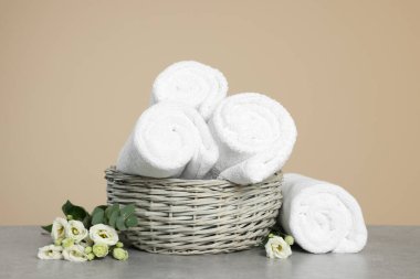 Gri masadaki hasır sepetin içinde yumuşak rulo havlular