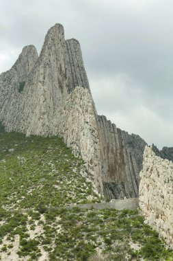 Kasvetli gökyüzü altında yüksek dağları olan resim gibi bir manzara.