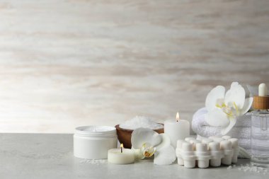 Farklı spa ürünleriyle güzel bir kompozisyon, açık gri masada mum ve çiçek yakmak. Metin için boşluk