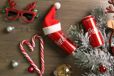 MYKOLAIV, UKRAINE - 01 Ocak 2021: Coca-Cola kutuları ve ahşap arka planda Noel süslemeleri ile yassı kompozisyon