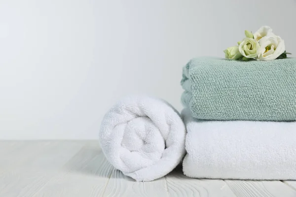Zachte Handdoeken Met Bloemen Houten Tafel Tegen Witte Achtergrond Ruimte — Stockfoto