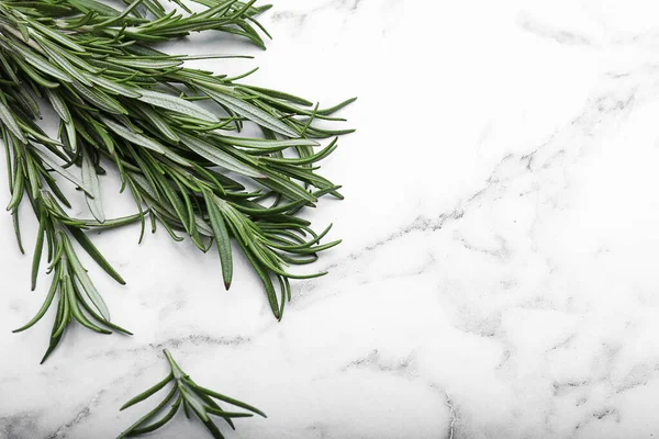 stock image Sprigs of rosemary on white marble table, flat lay. Space for text