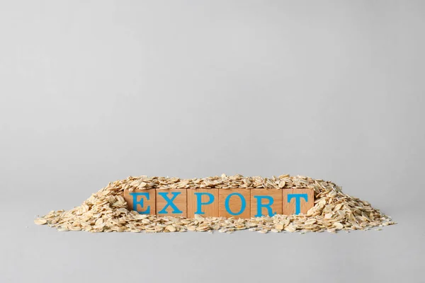 Pile of oatmeal and wooden cubes with word Export on grey background, space for text