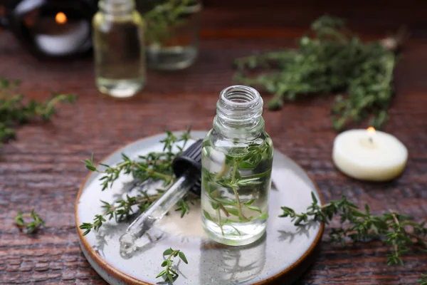 Thyme essential oil and fresh plant on wooden table, closeup