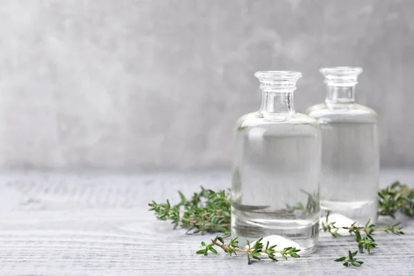 stock image Thyme essential oil on light blue wooden table, space for text