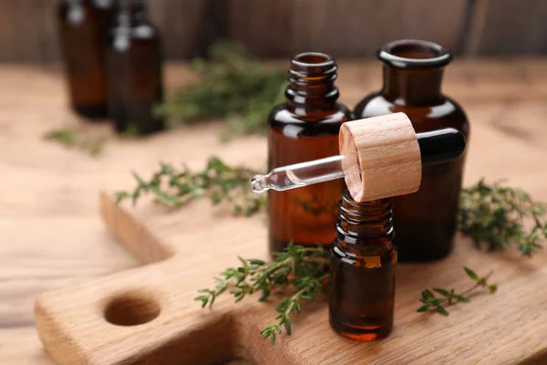 Thyme essential oil and fresh plant on wooden table