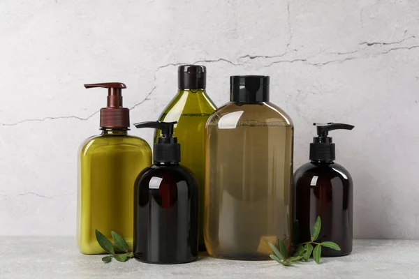 stock image Shampoo bottles and leaves on light grey table