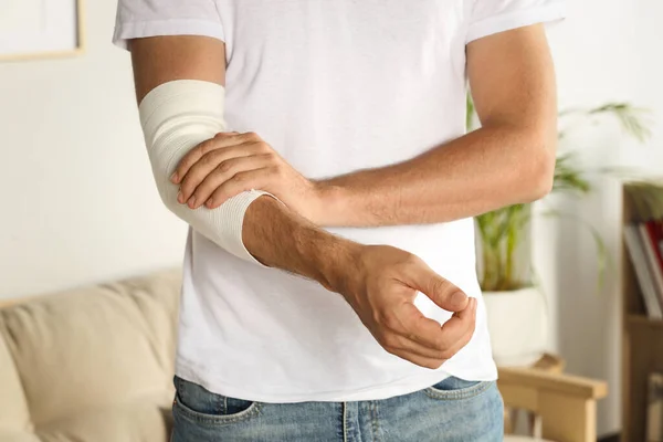 stock image Man with arm wrapped in medical bandage indoors, closeup