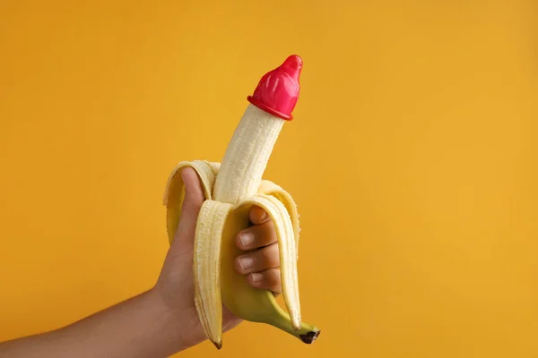 Γυναίκα Κρατώντας Μπανάνα Προφυλακτικό Πορτοκαλί Φόντο Closeup Και Χώρο Για — Φωτογραφία Αρχείου