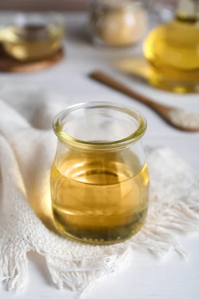 Jar of organic sesame oil on white wooden table, closeup