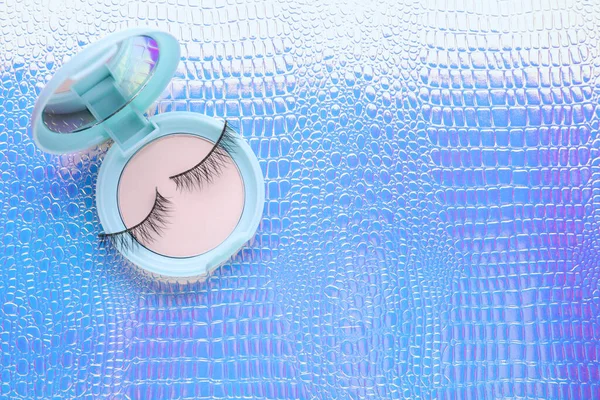 False eyelashes and cosmetic product on texture colorful background, top view. Space for text