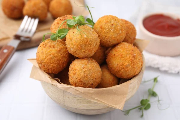 Bowl of delicious fried tofu balls with pea sprouts on white tiled table