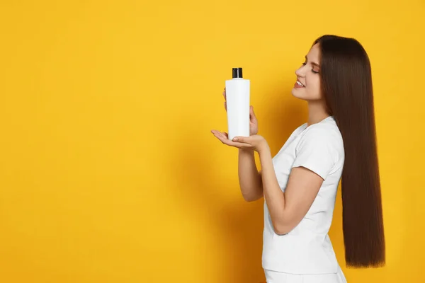 Bella Giovane Donna Che Tiene Una Bottiglia Shampoo Sfondo Giallo — Foto Stock