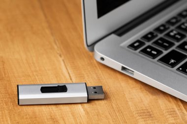 Modern dizüstü bilgisayar ve USB flash disk ahşap masada, yakın plan.