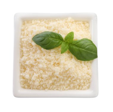 Parmesan peyniri rendelenmiş kare kase ve beyaz üzerine izole edilmiş fesleğen.