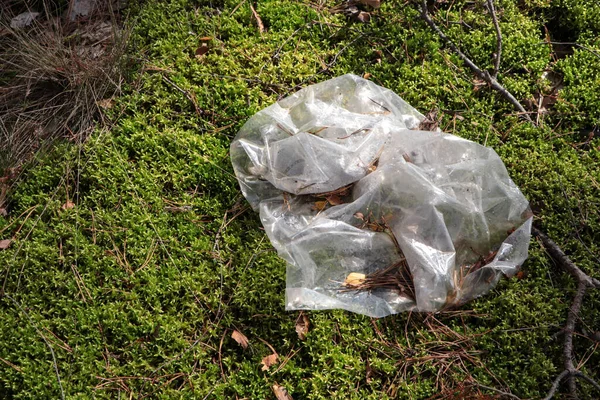 Disposable polyethylene bag on grass outdoors, top view. Recycling problem
