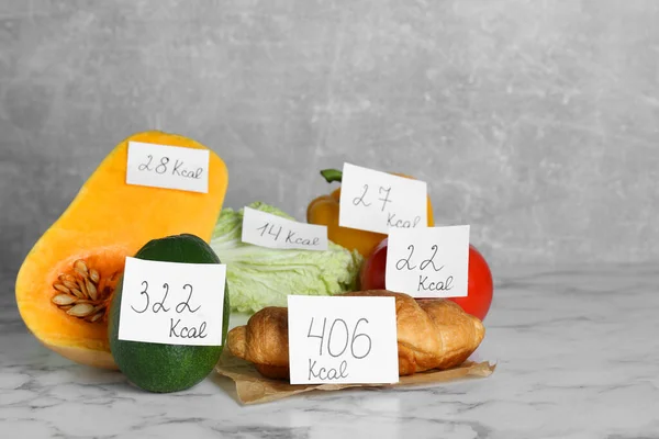 stock image Food products with calorific value tags on white marble table. Weight loss concept