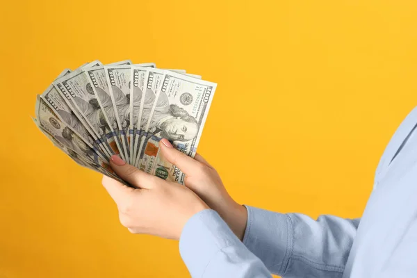 黄色の背景にドル紙幣を持っている女性 クローズアップ 貨幣交換の概念 — ストック写真
