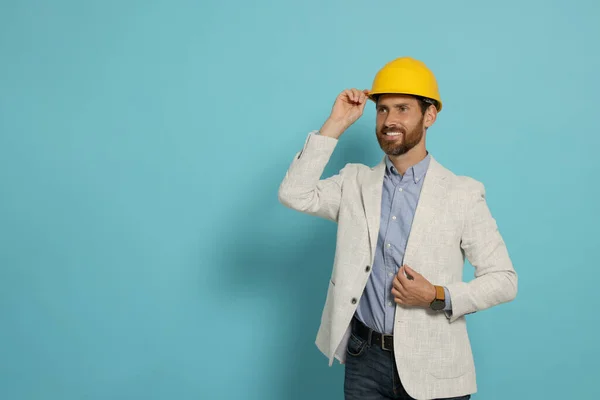 Professional engineer in hat on light blue background, space for text