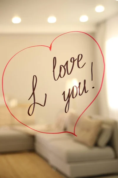 Drawn red heart with handwritten text I Love You on mirror in room. Romantic message
