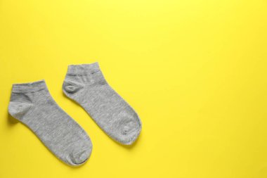 Sarı arka planda bir çift gri çorap, düz. Metin için boşluk